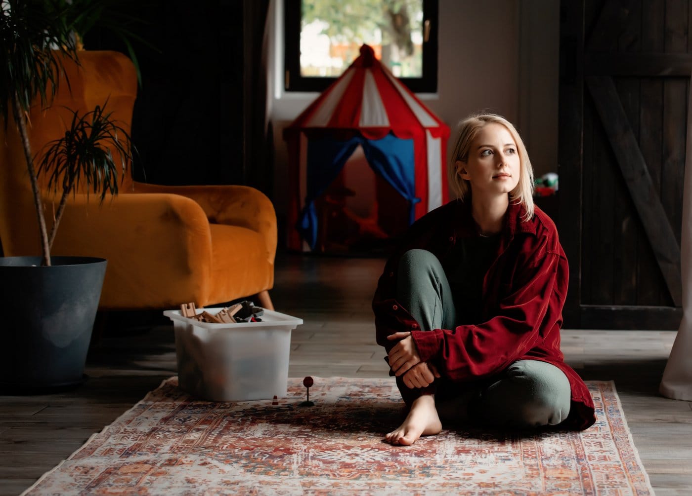 Divorced mom with joint custody sitting on the floor alone with toys nearby