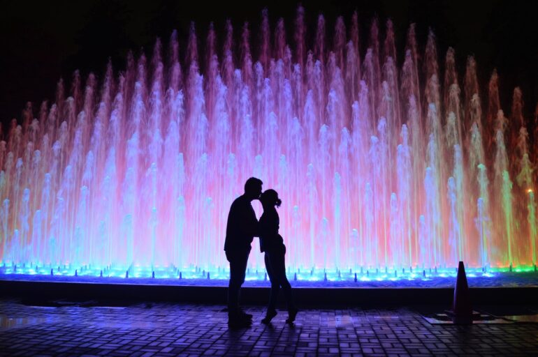 Romantic kiss in front of a lighted fountain
